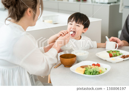 一位母親在餐桌上餵兒子吃飯。 138806197