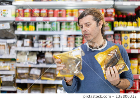 Adult man choosing dried fish at grocery store Adult man choosing dried fish at grocery store 138806312