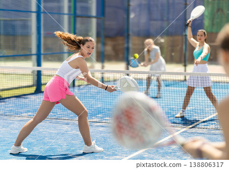 Young woman playing paddle tennis against team of women 138806317