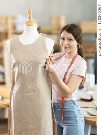 Female tailor sews new dress on a mannequin in sewing studio Female tailor sews new dress on a mannequin in sewing studio 138806367