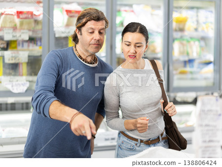 Adult couple choosing frozen food in grocery store Adult couple choosing frozen food in grocery store 138806424