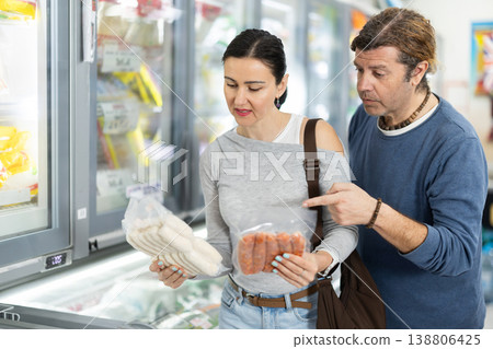 Couple in supermarket choose cooled raw sausages Couple in supermarket choose cooled raw sausages 138806425