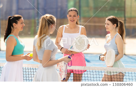 Female padel tennis players chatting on tennis court Female padel tennis players chatting on tennis court 138806460