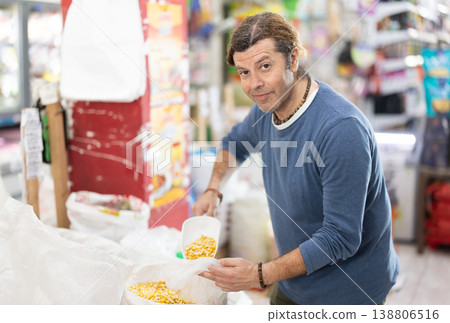 Man in store takes maize cereal out of sack, pours dose of cereal into bag Man in store takes maize cereal out of sack, pours dose of cereal into bag 138806516