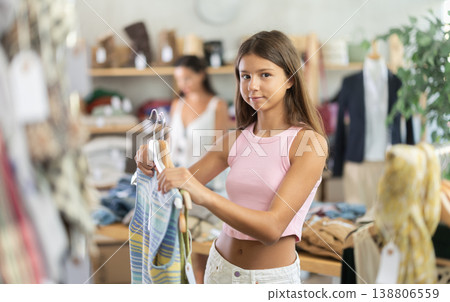 Happy teenage girl choosing something for summer in clothing store Happy teenage girl choosing something for summer in clothing store 138806559