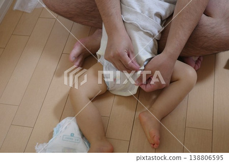 爸爸幫孩子換完尿布後，又幫他換了衣服。 138806595