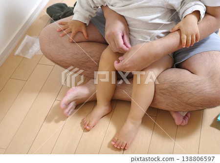 家中,父親正抱著嬰兒幫孩子換尿布。 家中,父親正抱著嬰兒幫孩子換尿布。 138806597
