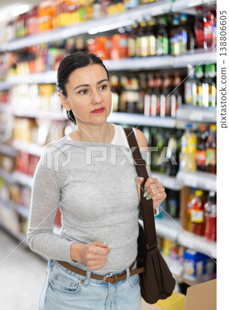 In food store, woman looking for something on shelf of showcase In food store, woman looking for something on shelf of showcase 138806605