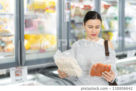 Woman in supermarket choose cooled raw sausages 138806642