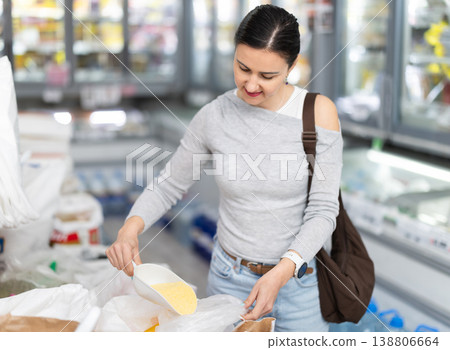 Adult woman pours corn flour into bag at store 138806664