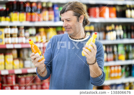 Adult man choosing honey in grocery store Adult man choosing honey in grocery store 138806676