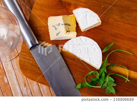 Sliced creamy blue cheese on wooden table with knife and arugula Sliced creamy blue cheese on wooden table with knife and arugula 138806689