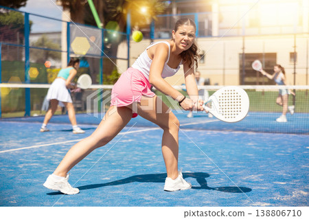 Young woman playing paddle tennis against team of women 138806710