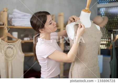 Woman seamstress adjusts clothes on mannequin Woman seamstress adjusts clothes on mannequin 138806728