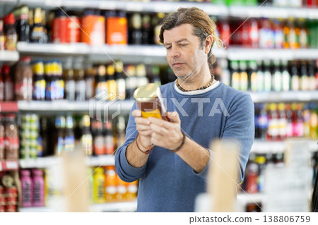 Man customer in supermarket choose honey, buy food stuff in grocery store Man customer in supermarket choose honey, buy food stuff in grocery store 138806759
