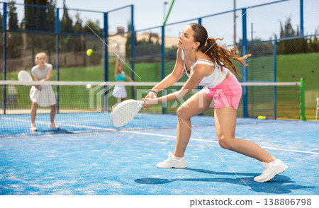 Young woman playing paddle tennis against team of women 138806798