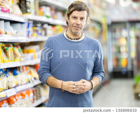 In food store, man looking for something on shelf of showcase In food store, man looking for something on shelf of showcase 138806810