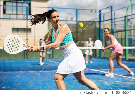 Adult woman plays paddle tennis against team of women Adult woman plays paddle tennis against team of women 138806824