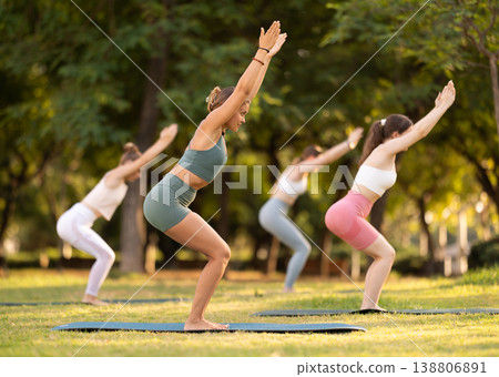 Athletic girls meditates in yoga pose parshvottanasana in summer sunny park. Demonstration of various yoga poses 138806891