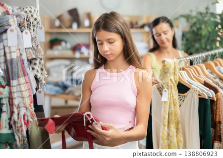 Teen girl customer choose handbag in store Teen girl customer choose handbag in store 138806923