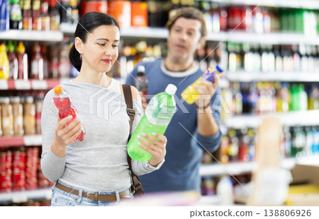 Couple adult man and woman choosing soft drinks in store Couple adult man and woman choosing soft drinks in store 138806926