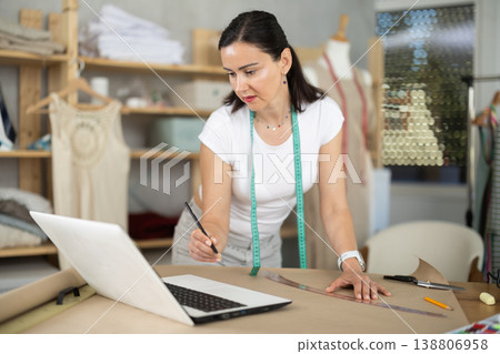 Woman tailor uses computer when creating drawing of future product Woman tailor uses computer when creating drawing of future product 138806958