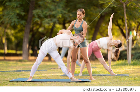 Coach corrects Trikonasana position, helps to perform exercise correctly. 138806975