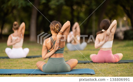 Yoga lesson visitors girls perform Paschima Namaskarasana in park Yoga lesson visitors girls perform Paschima Namaskarasana in park 138806991