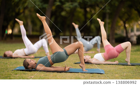 Athletic girls leading an active lifestyle, training in a summer park, performing dynamic asanas to improve body flexibility 138806992