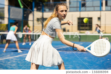 Young woman playing paddle tennis against team of women Young woman playing paddle tennis against team of women 138806994