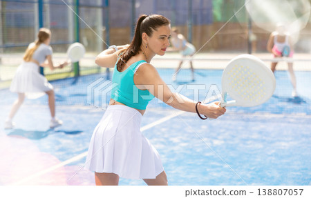 Adult woman plays paddle tennis against team of women 138807057