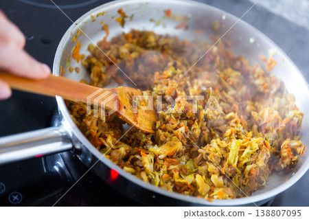 Hand stirring chopped cabbage in pan Hand stirring chopped cabbage in pan 138807095