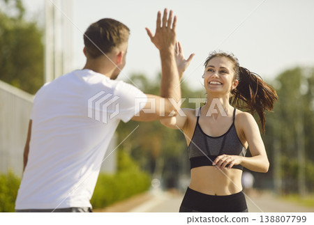 Happy sporty couple man and woman giving high five each other rejoicing the success in jog training Happy sporty couple man and woman giving high five each other rejoicing the success in jog training 138807799