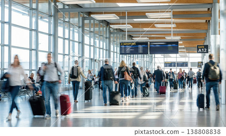 busy modern airport interior hall showing many traveling people walking with wheeled suitcases towards departure gates below large flight schedule display screens transit journey busy modern airport interior hall showing many traveling people walking with wheeled suitcases towards departure gates below large flight schedule display screens transit journey 138808838