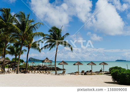 Empty sunbeds and umbrellas on tropical beach in Mauritius resort. Empty sunbeds and umbrellas on tropical beach in Mauritius resort. 138809008