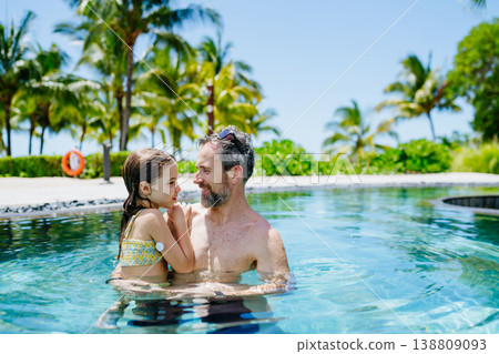 Family playing in tropical resort pool, child with diabetes wears glucose monitor. Family playing in tropical resort pool, child with diabetes wears glucose monitor. 138809093