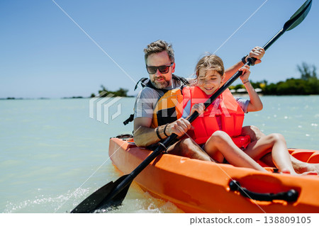 Father kayaking with daughter on calm sea during family summer vacation. Father kayaking with daughter on calm sea during family summer vacation. 138809105