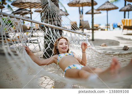 Smiling girl relaxing in hammock during tropical family vacation. 138809108