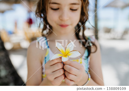 Happy child smelling tropical flower during family vacation at beach resort. 138809109