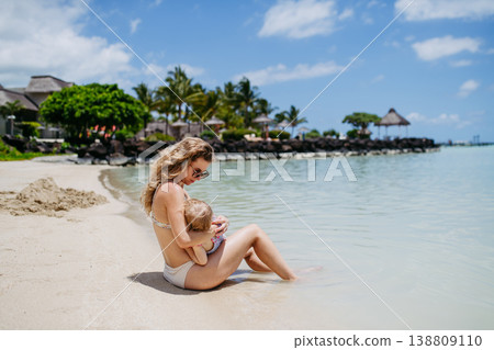 Mom breasfeeding little child on beach. 138809110