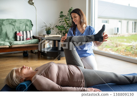 Physiotherapist exercising with senior woman on gym mat. Physiotherapist exercising with senior woman on gym mat. 138809130
