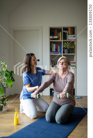 Physiotherapist exercising with senior woman on gym mat. 138809150