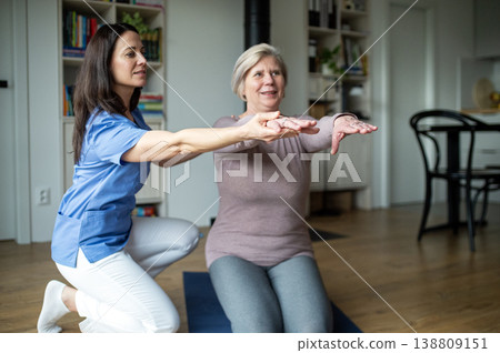 Physiotherapist helping senior woman during rehabilitation exercise at home. Physiotherapist helping senior woman during rehabilitation exercise at home. 138809151