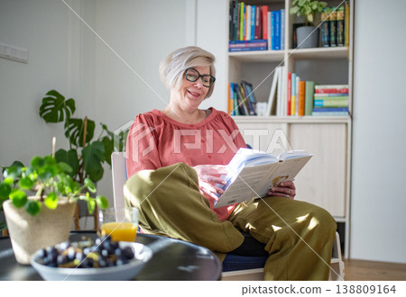 Smiling elderly woman reading book at home. 138809164