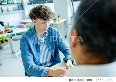 Teacher supporting struggling student. Boy confiding in a teacher. Teacher supporting struggling student. Boy confiding in a teacher. 138809200