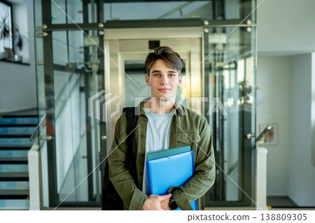 Teen student standing by lockers in school hallway. 138809305