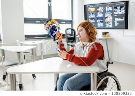 Female student in wheelchair presenting robotic project in front of classroom. 138809323