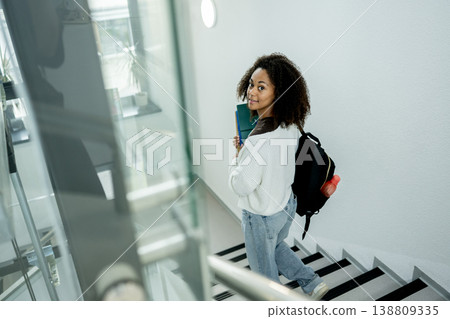 College student moving through building with study materials and backpack. College student moving through building with study materials and backpack. 138809335