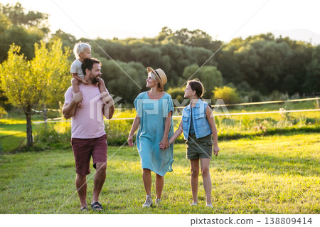 Family on walk in summer nature, standing under apple tree. 138809414