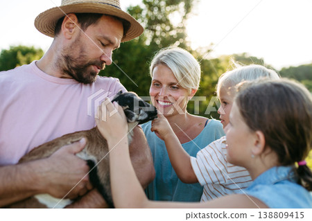 Family petting little goat at farm. 138809415